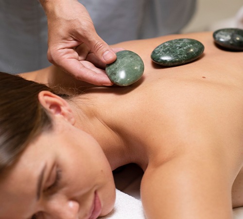 Woman receiving a hot stone massage with stones placed along her back