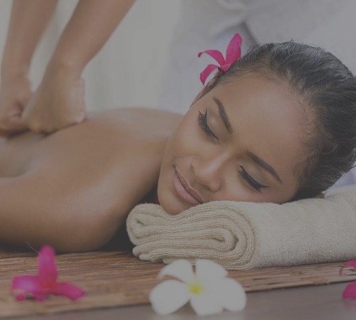 Woman receiving a relaxing back massage with tropical flowers in a spa setting